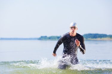 Triathlete running out of the water on triathlon race.